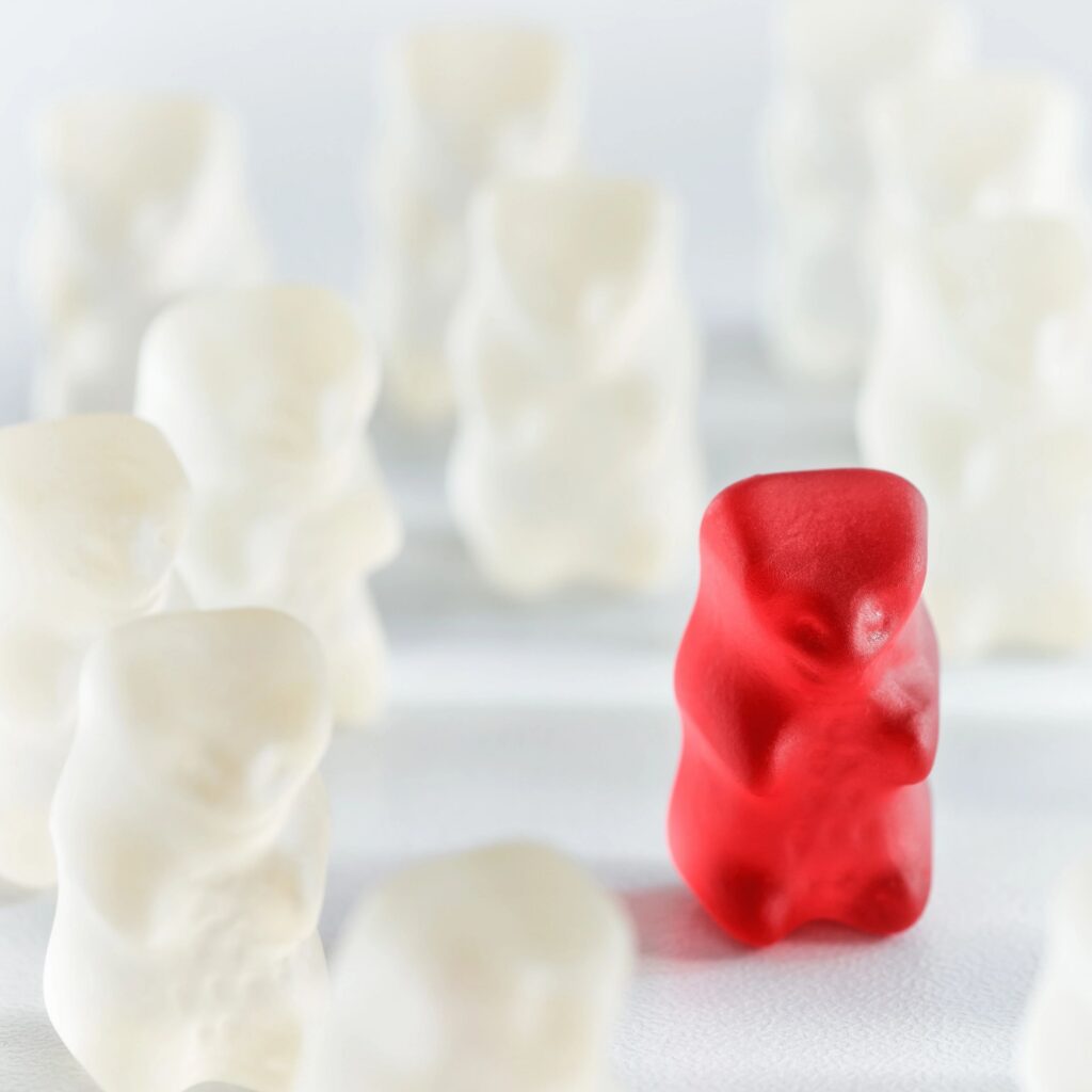 Red gummy bear candy standing out from the crowd arrangement close-up studio shot